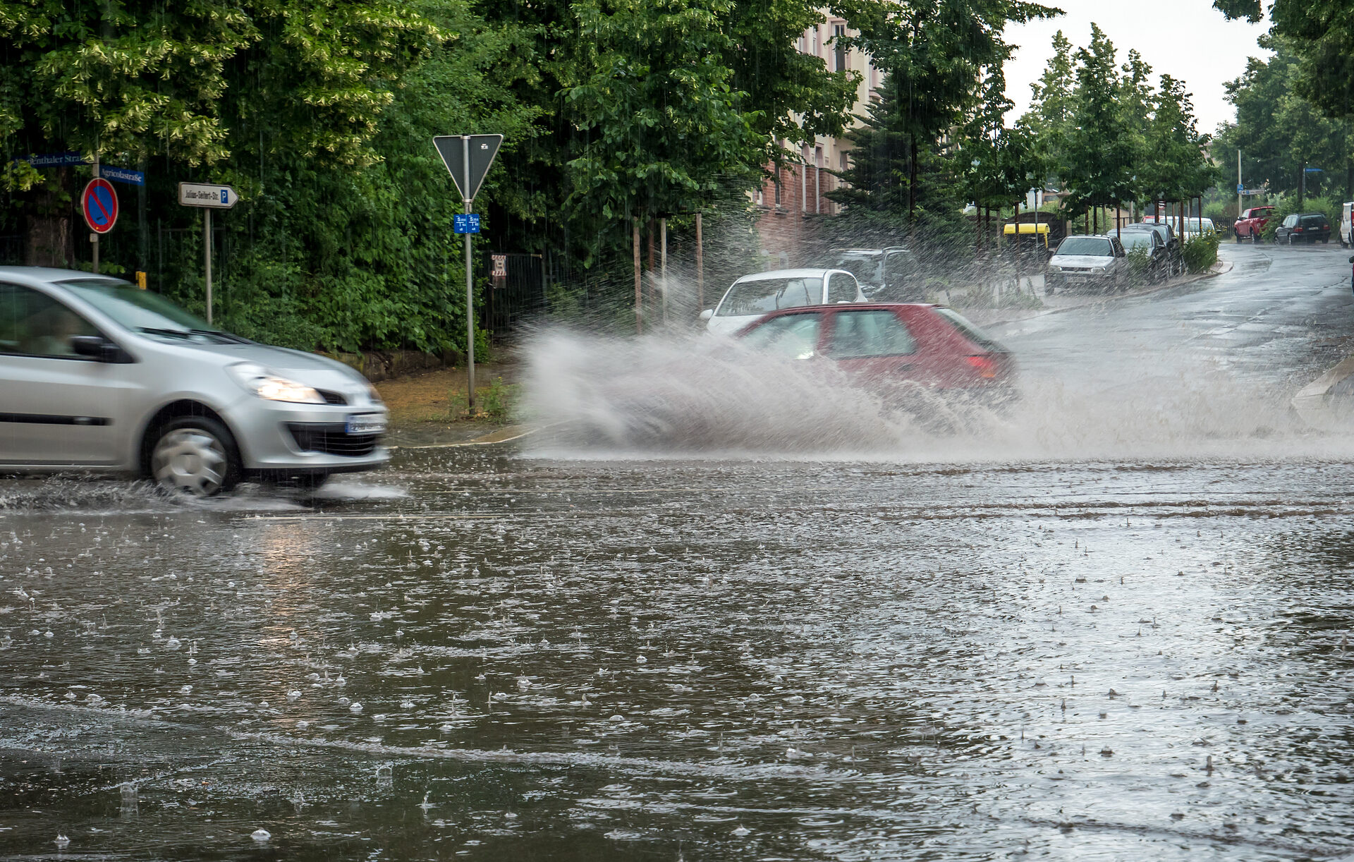 Autos fahren nach Starkregen durch überflutete Straßen